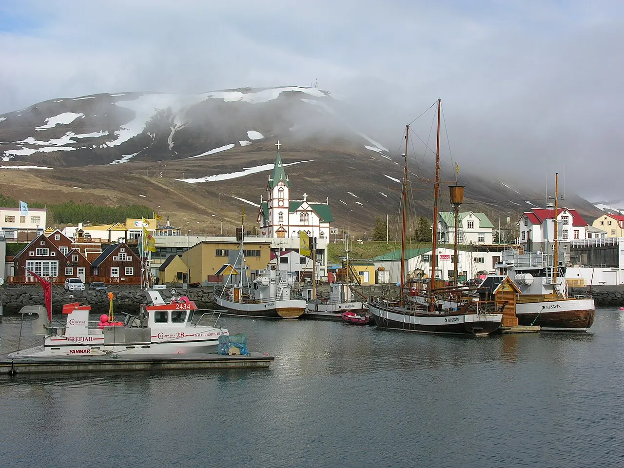 Wooden boats in Húsavík harbor below the town church